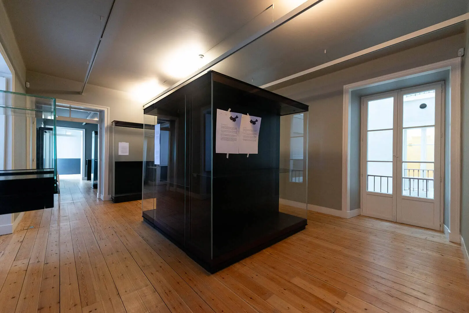 Empty exhibition room during installation, with a dark display case in the centre