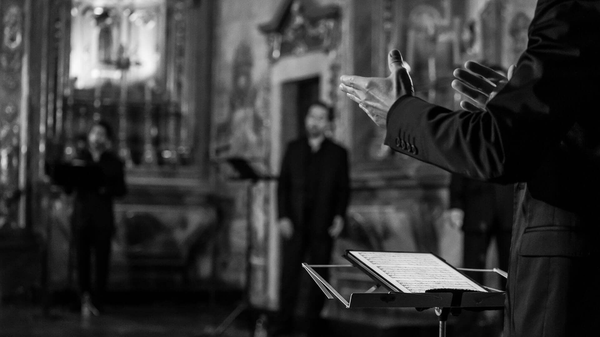 Maestro e sua pauta com cantor ao fundo durante a Temporada Música em São Roque