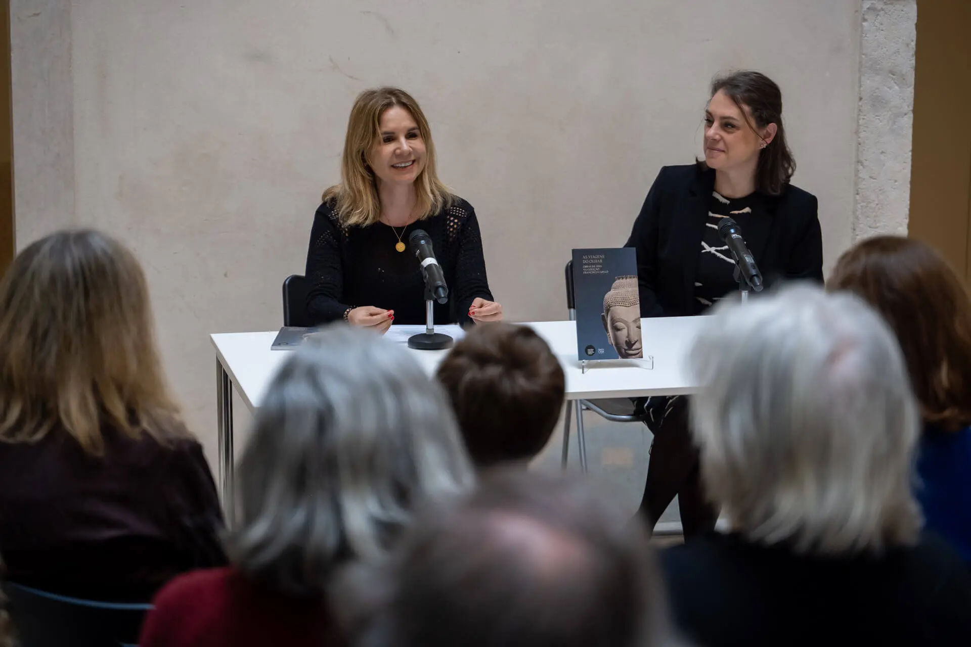 Rita Prates e Teresa Nicolau sentadas a uma mesa, na apresentação do Roteiro, diante do público