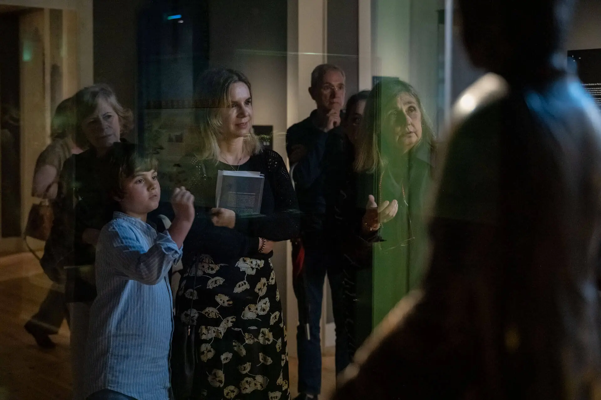 Rita Prates, Teresa Nicolau e Eduarda Napoleão, com outros visitantes, a ver uma peça numa sala de exposição