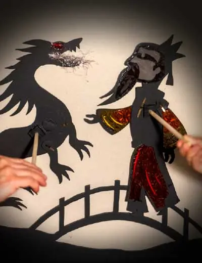 Marionetas de papel de um dragão e de um imperador, numa ponte, na peça «O Canto do Tsuru»
