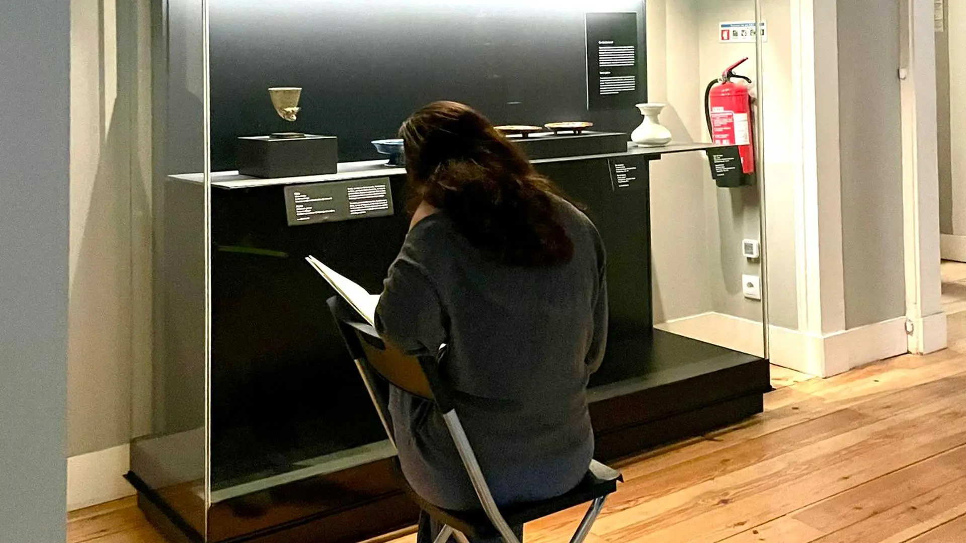 Aluna sentada a desenhar diante de uma vitrine