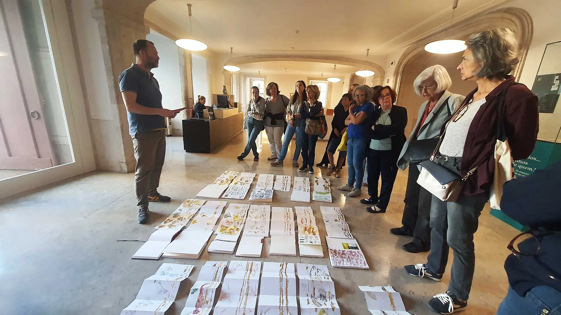 Mário Linhares e participantes do workshop de pé, a ver desenhos espalhados no chão