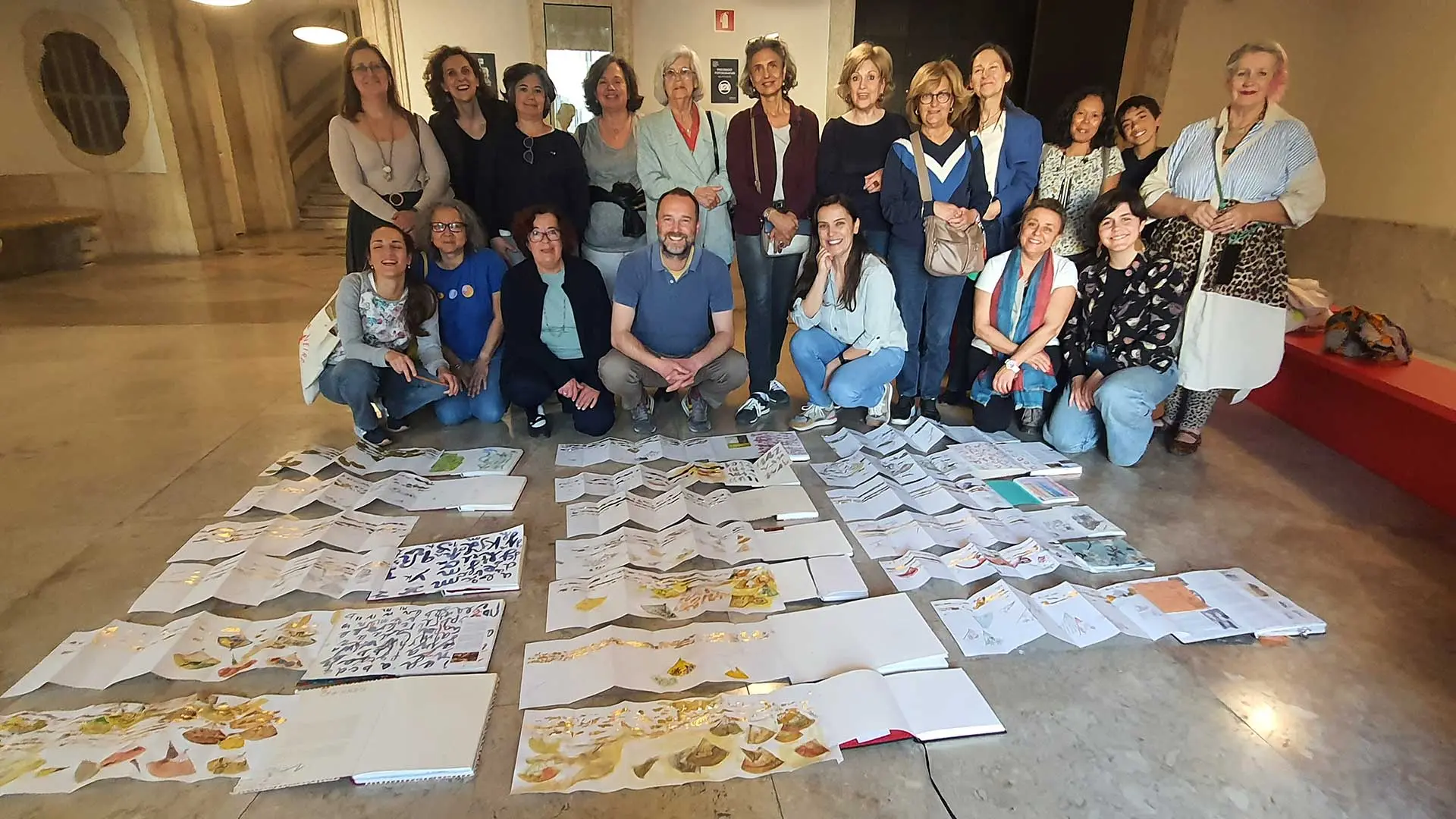 Mário Linhares e participantes do workshop, em grupo, atrás dos desenhos espalhados no chão