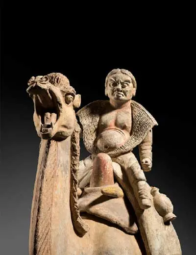 Escultura de uma figura montada num camelo, sobre fundo preto