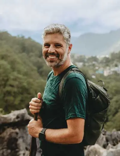 Luís Simões, sorridente, de mochila, numa paisagem de montanha
